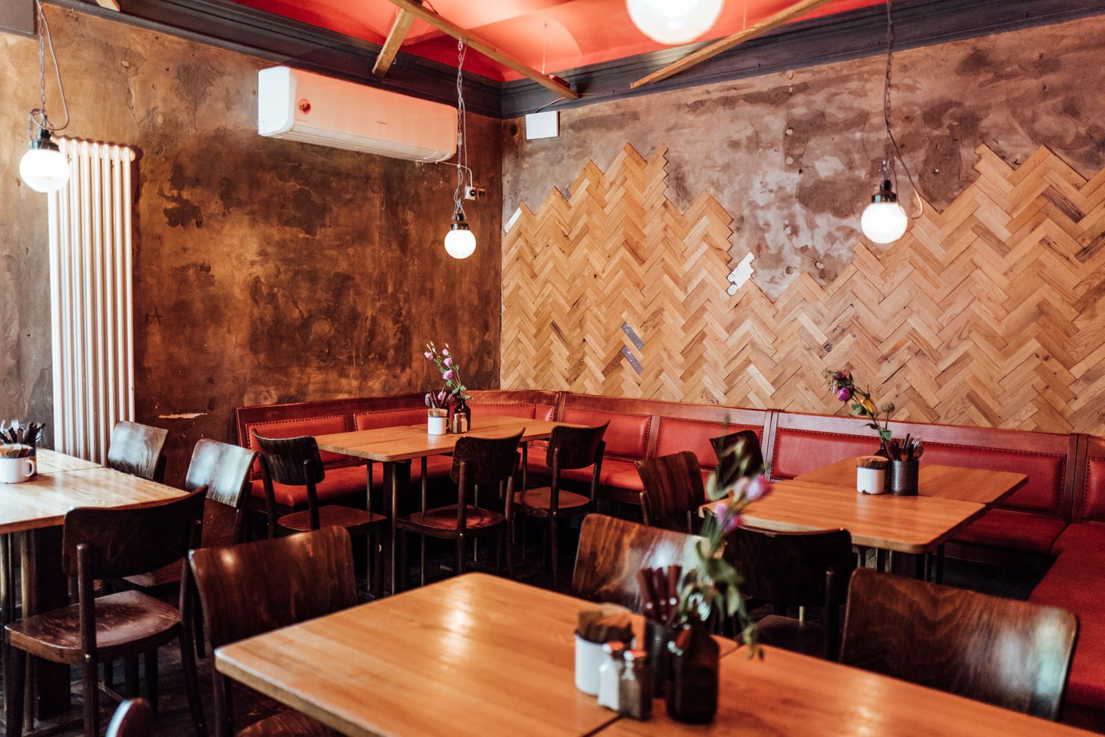 Innenansicht von "Otto's Burger" mit Holzvertäfelung, roten Lederbänken, Holztischen und Stühlen.