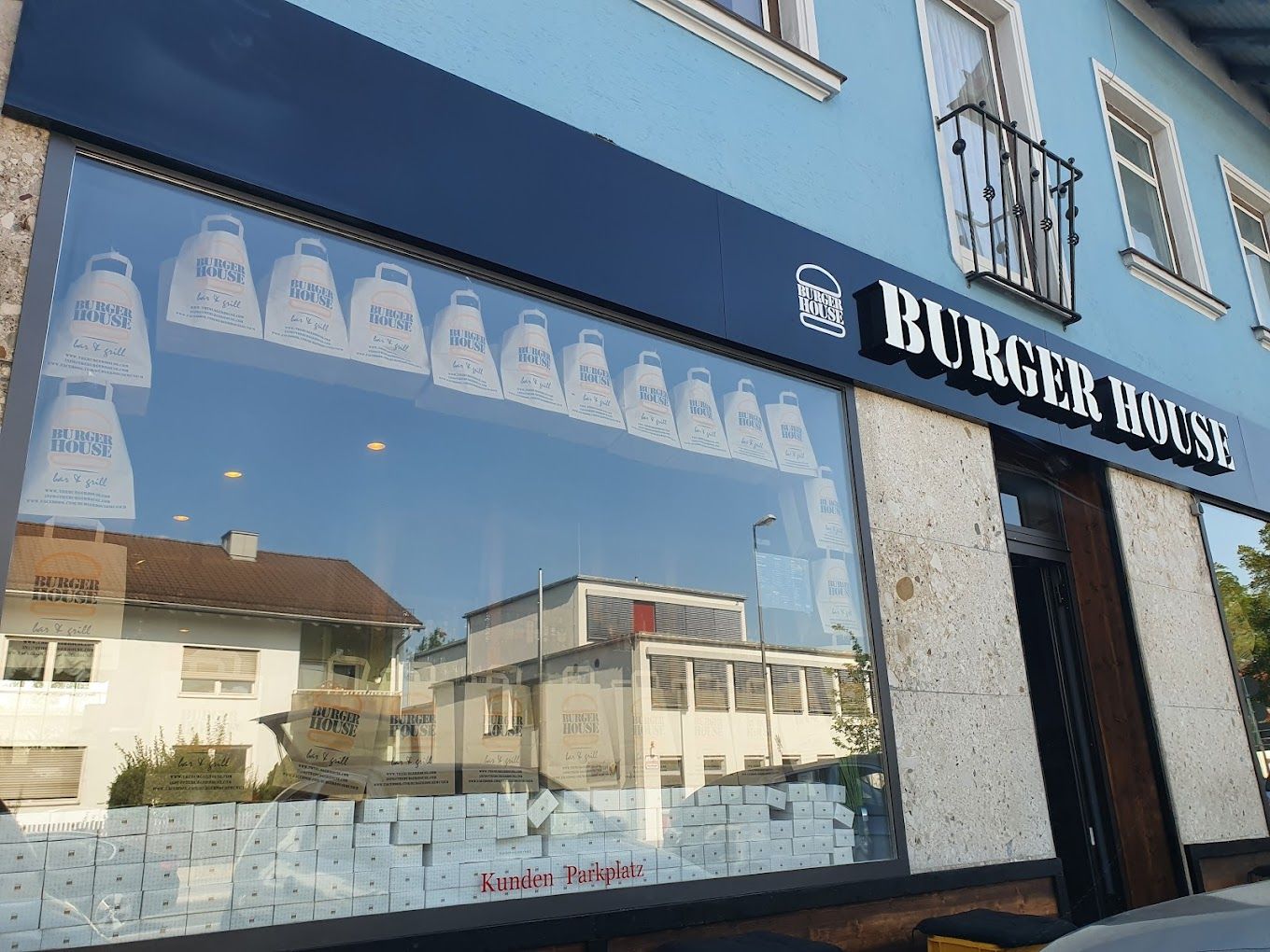Außenansicht von "Burger House" mit  großem Schaufenster, dekoriert mit "Burger House" ToGo-Tüten.